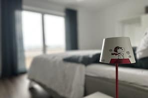 Quarto de hotel com uma cama, uma janela e um abajur do Snoopy.