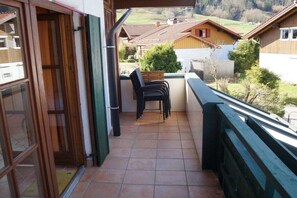 Ein Balkon mit Blick auf Häuser, eine Tür und einen Stuhl.