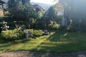 En trädgård med stenskulpturer, en träkonstruktion och en stenlykta.