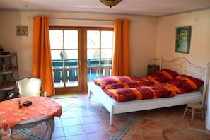 A bedroom with a bed, a table, a chair, and a balcony. - Lake Constance mountain view with winter garden (Oberstaufen)
