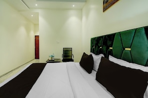 Una habitación de hotel con una cama grande, una mesita de noche, una silla y un cuadro en la pared.