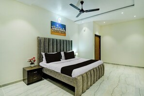 A modern bedroom with a large bed, a nightstand, a wall-mounted painting, and a ceiling fan. - Collection O Amer Jaipur (Jaipur)