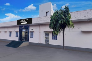 A building with a sign that reads 'Collection Company Serviced'. There are steps leading to the entrance, and a tree is in front of the building. - Collection O Amer Jaipur (Jaipur)