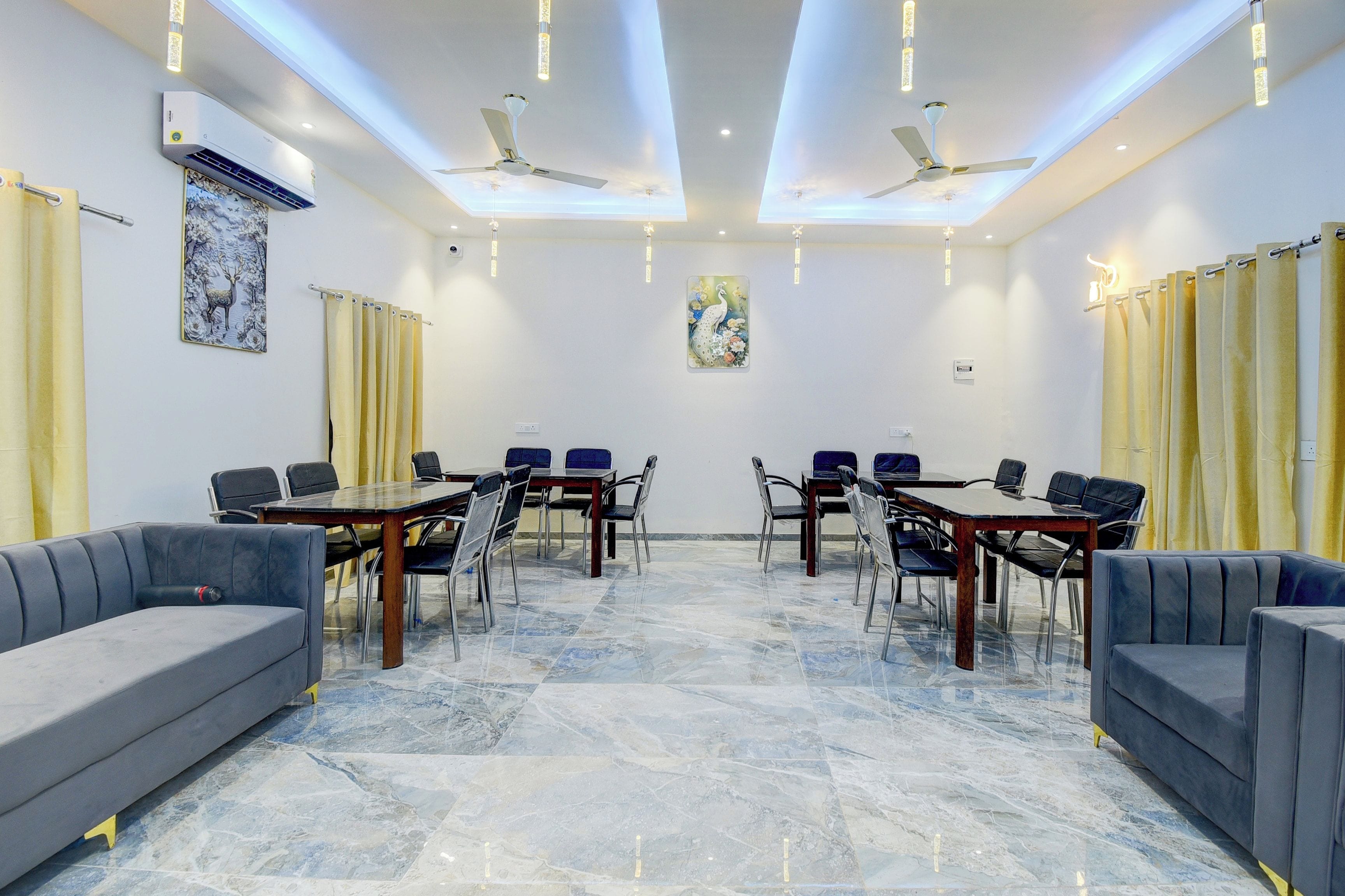 A conference room with a marble floor, two sofas, a table with chairs, ceiling fans, and decorative wall art.