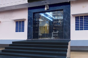 A building entrance with a black metal gate, a set of stairs leading up to it, and a blue-framed window on the left. - Collection O Amer Jaipur (Jaipur)