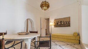 A dining area with a round table, chairs, and a chandelier. There is a sofa and a lamp in the background. - Peaceful 5-Bedroom Riad in the Heart of Marrakech (Marrakesh)