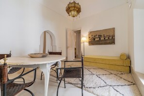 A dining area with a round table, chairs, and a chandelier. There is a sofa and a lamp in the background. - Peaceful 5-Bedroom Riad in the Heart of Marrakech (Marrakesh)