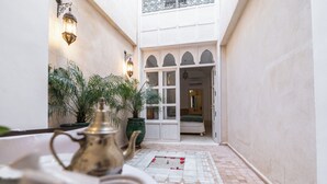A narrow courtyard with a tiled floor, a bed visible through an open door, and potted plants. - Peaceful 5-Bedroom Riad in the Heart of Marrakech (Marrakesh)