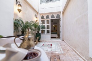 A narrow courtyard with a tiled floor, a bed visible through an open door, and potted plants. - Peaceful 5-Bedroom Riad in the Heart of Marrakech (Marrakesh)