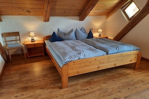A bedroom with a wooden bed, two bedside tables, a chair, and a window. - in the old forester's lodge (Riedlhütte)