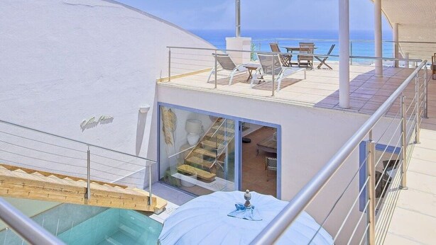 Terrassa moderna a la teulada amb piscina, mobiliari exterior i vista a l'oceà.