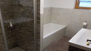 Une salle de bain avec une douche à parois de verre, une baignoire et un lavabo.