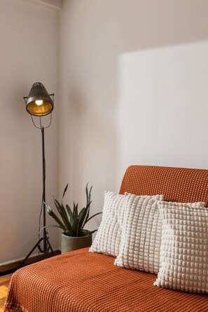 A bedroom with a bed, a floor lamp, a potted plant, and a textured throw blanket. - Andromeda: Cozy 2BD apartment in the center with spacious balcony (Thessaloniki)