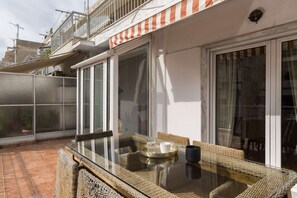 A glass-top table with wicker chairs and a tray, set on a balcony with a view of the city. - Andromeda: Cozy 2BD apartment in the center with spacious balcony (Thessaloniki)