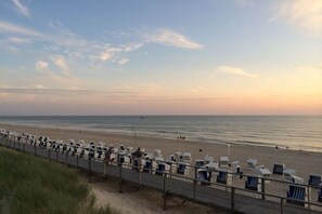 Ein Strand mit Liegestühlen und einer Holzstege.