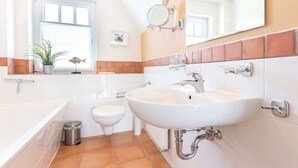 Ein Badezimmer mit Waschbecken, Toilette, Bidet, Spiegel und Fenster.