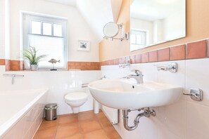 Ein Badezimmer mit Waschbecken, Toilette, Bidet, Spiegel und Fenster.