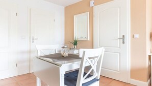 Ein Essbereich mit Tisch und Stühlen, ein Spiegel an der Wand und eine Tür.