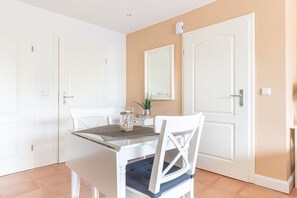 Ein Essbereich mit Tisch und Stühlen, ein Spiegel an der Wand und eine Tür.