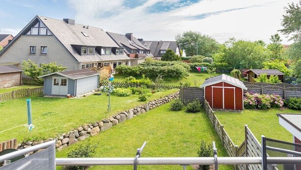 Ein Wohngebiet mit Häusern, einem kleinen Gartenhaus und einem gepflegten Rasen.