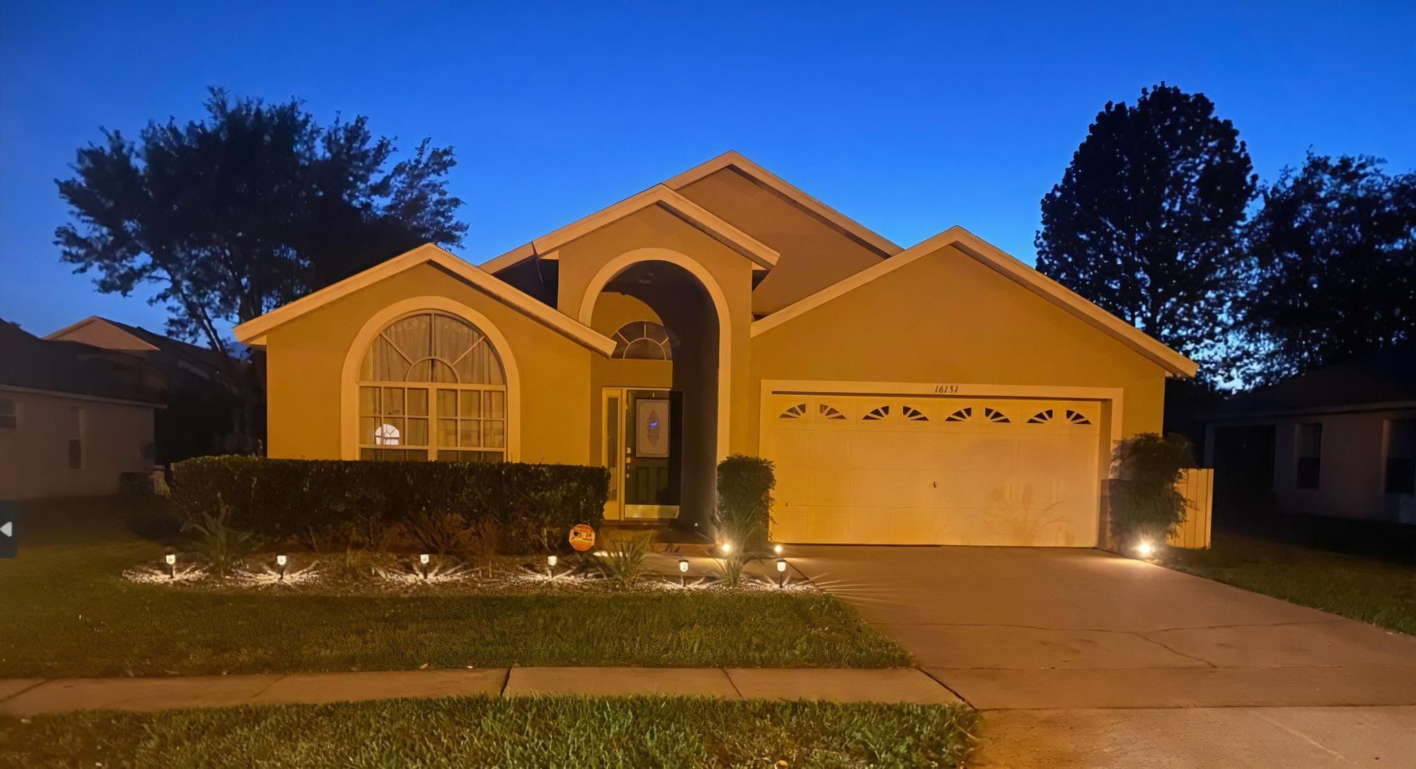 A residential house with a garage, a driveway, and a well-maintained lawn.
