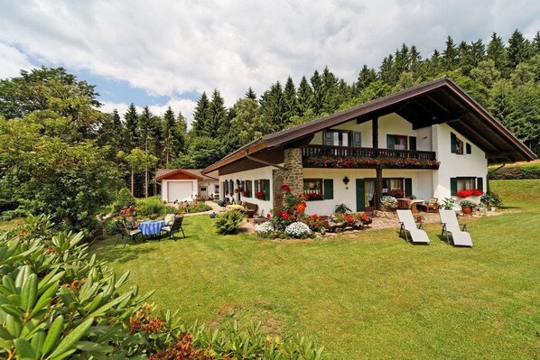Eine zweistöckige Chalet mit Balkon, umgeben von einem gepflegten Garten und einem Pool.