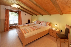 Ein Schlafzimmer mit einem hölzernen Bett, Nachttischen, einem Sessel und einem Fenster mit Vorhängen.