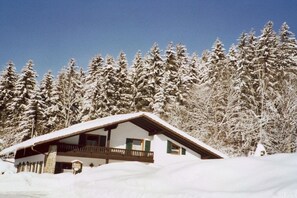 Eine schneebedeckte Lodge mit Balkon und freiem Blick auf schneehohe Bäume.
