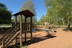 Ein Spielplatz mit einer Holzkonstruktion, einer Rutsche und Klettergeräten.