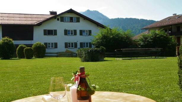Ein Tisch draußen gedeckt mit einer Weinflasche, Gläsern und einer Speisekarte.