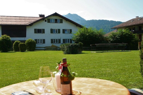 Mesa posta ao ar livre com garrafa de vinho, copos e cardápio.