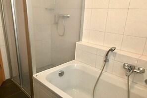 Casa de banho com banheira, zona de duche e cabine de hidromassagem em vidro.