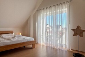 Quarto com cama, luminária em formato de estrela e vista através de cortinas leves.