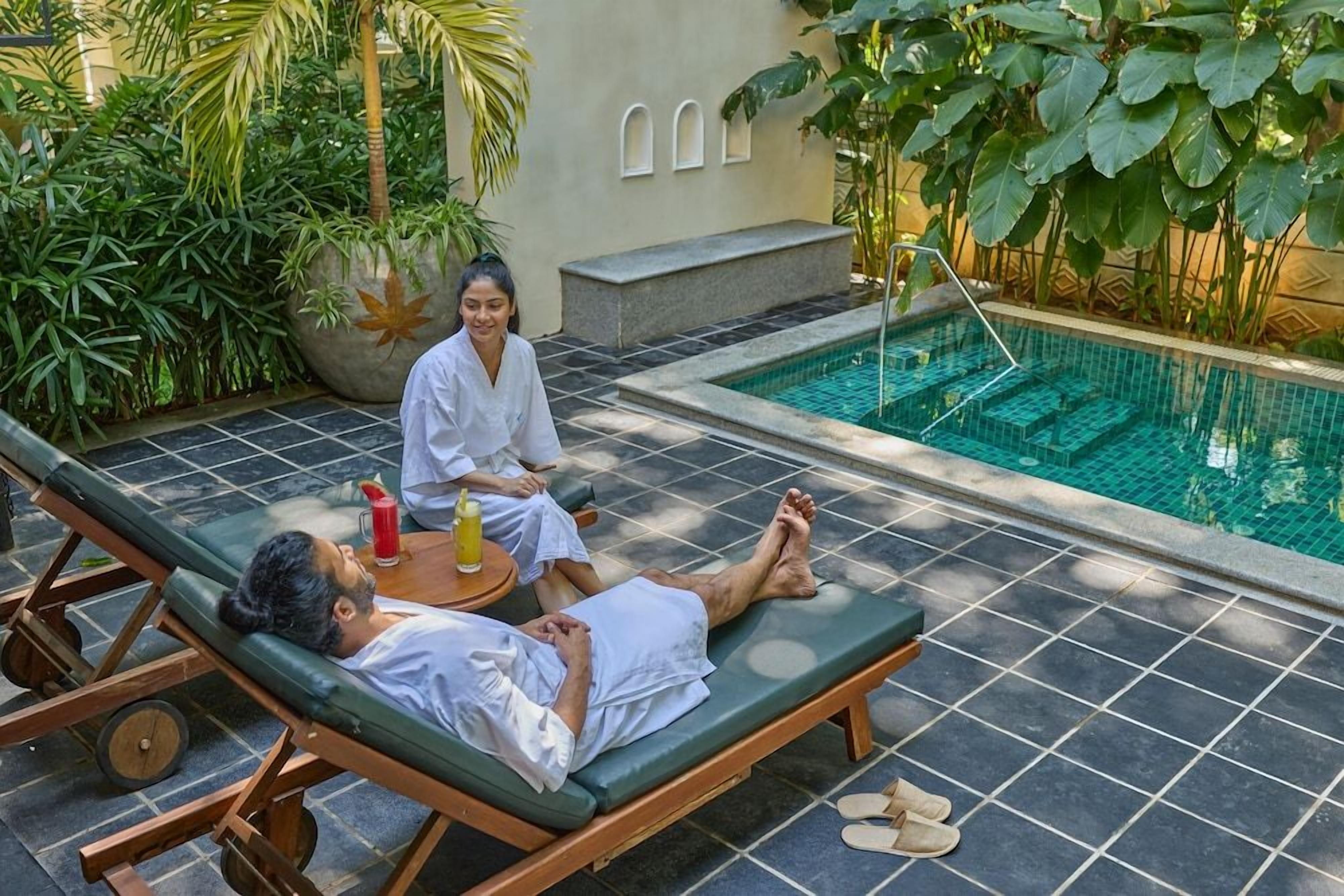 A poolside area with lounge chairs, a small table with drinks, and a water feature.