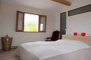 Ein Schlafzimmer mit Bett, Stuhl, Fenster und Spiegel.