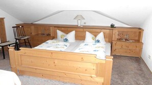 Een slaapkamer met een houten bed, twee nachtkastjes, een stoel en een lamp.