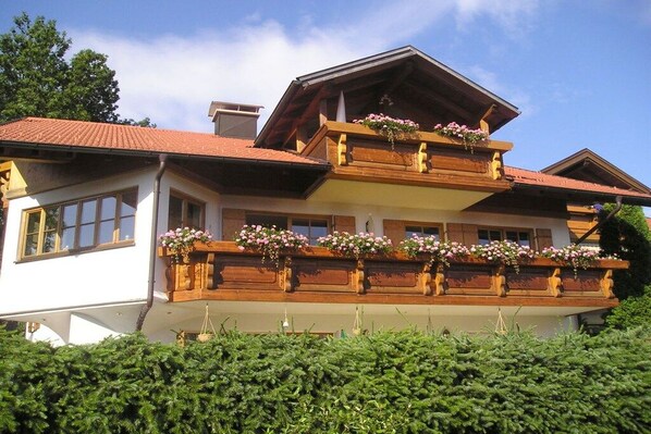 Um edifício de dois andares com uma varanda decorada com floreiras.