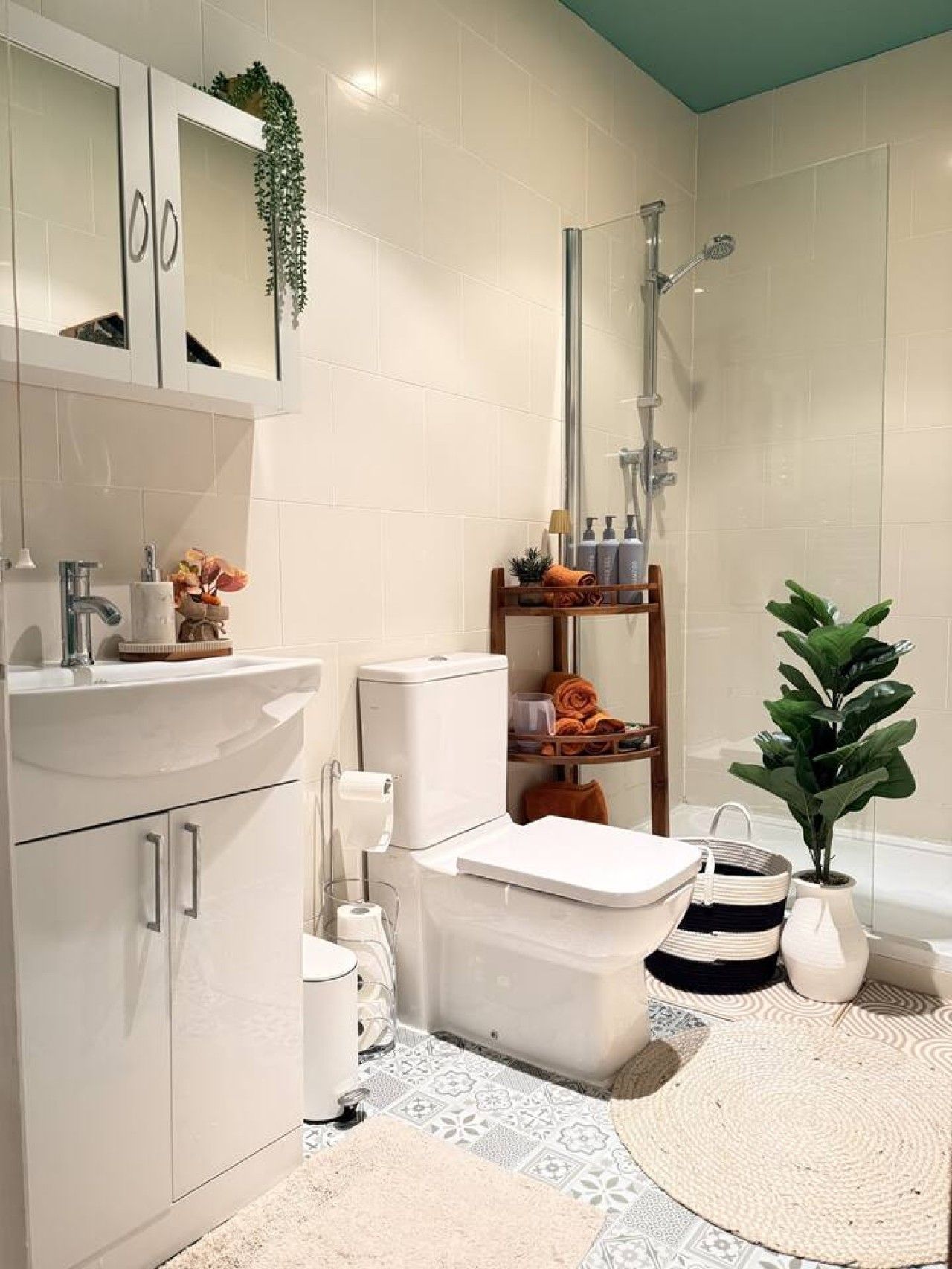 A modern bathroom with a toilet, bidet, and shower. There are towels, toiletries, and a plant on shelves.