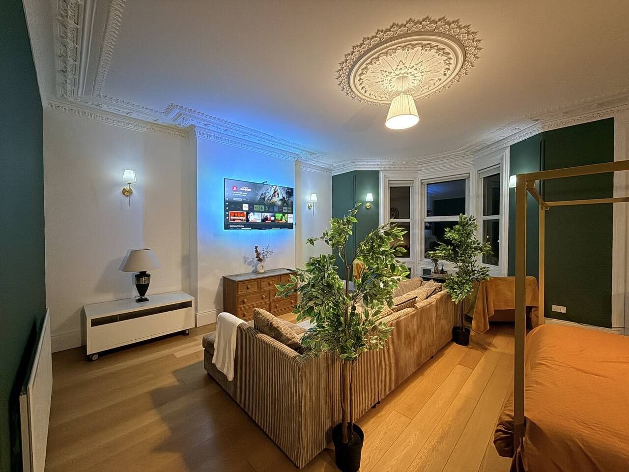 A modern living room with a sofa set, a television, and a decorative ceiling.