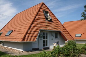 A house with a steeply pitched roof, a small porch, and a window with a view. - Holiday home with 1 bedroom (Wurster Nordseeküste)