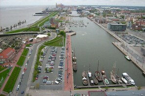 A marina with boats docked, a parking lot, and a cityscape in the background. - Holiday home with 1 bedroom (Wurster Nordseeküste)