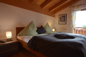 A bed with a wooden headboard, a nightstand with a lamp, and a framed picture on the wall. - Holiday home in Allgäu with 3 bedrooms (Lechbruck am See)