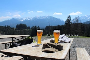 A picnic table with two beer glasses and a cap, set against a mountainous backdrop. - Holiday home in Allgäu with 1 bedroom (Lechbruck)