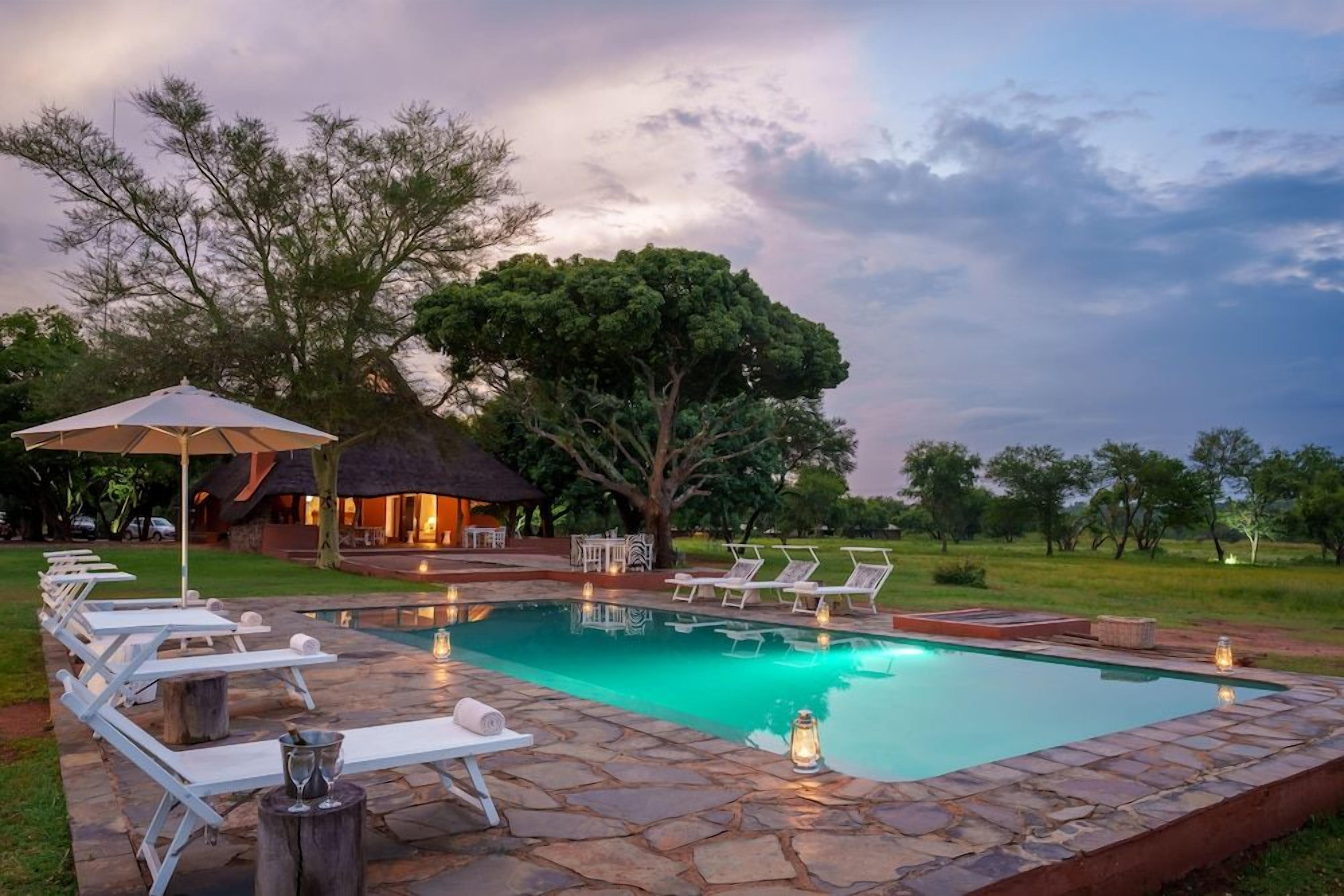 A swimming pool with lounge chairs and a thatched-roof structure.
