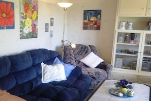 Ein Wohnzimmer mit einem dunkelblauen Sofa, einem gemusterten Sessel und einem Couchtisch mit Dekoration.