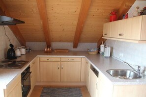 Eine Küche mit Holzschränken, einem Herd, einem Spülbecken und einem Deckenventilator.