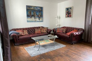 Ein Wohnzimmer mit zwei Ledersofas, einem Glastisch und einem Teppich.