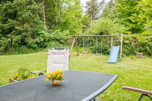 Ein Garten mit Trampolin, Schaukel und Rutsche.