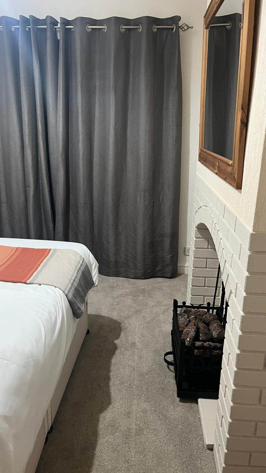A bedroom with a bed, a fireplace, and a curtain.