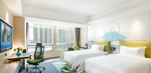 Habitación de hotel con dos camas, un escritorio, una silla, un televisor y un amplio ventanal con vista a la ciudad.
